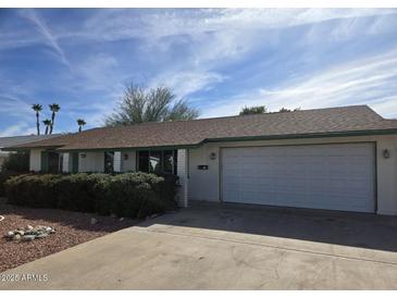 Ranch-style home with a two-car garage and well-manicured landscaping at 9325 W Arrowhead Dr, Sun City, AZ 85351