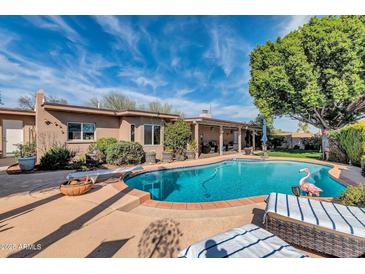 Inviting backyard pool with lounge chairs and a covered patio, perfect for outdoor relaxation and entertainment at 14615 N 28Th St, Phoenix, AZ 85032