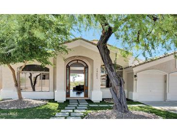 Inviting front entrance with decorative stone walkway and arched doorway, complemented by mature desert landscaping at 24084 N 77Th St, Scottsdale, AZ 85255