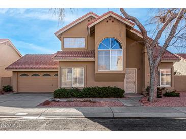 Charming two-story home featuring a red tile roof, arched window, desert landscaping, and two-car garage at 3801 E Kent Dr, Phoenix, AZ 85044