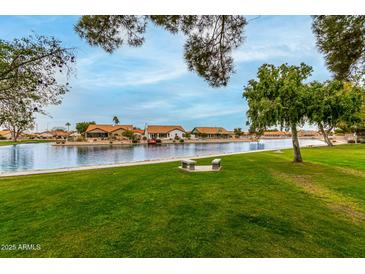 Picturesque community lake view with green grass and neighborhood houses in a tranquil setting at 10971 W Tonopah Dr, Peoria, AZ 85373