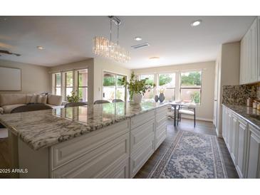 Bright kitchen features granite counters, a large island with seating, and views to the living room and backyard at 2073 E Wildhorse Dr, Chandler, AZ 85286