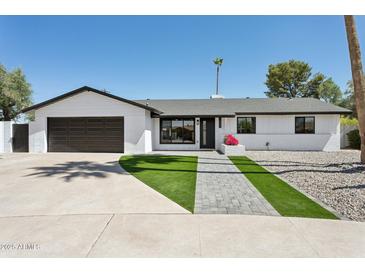 Charming home featuring a well-manicured front yard, lush lawn, and a classic black and white color scheme at 2217 N 79Th St, Scottsdale, AZ 85257