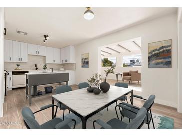 Bright dining area featuring modern table set, hardwood floors, and open flow to the updated kitchen at 2227 W Paradise Dr, Phoenix, AZ 85029