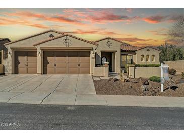 Inviting home featuring a 3-car garage, desert landscaping, and classic Southwestern architecture at sunset at 30696 N 130Th Ln, Peoria, AZ 85383