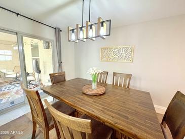 Bright dining area with a wooden table, stylish lighting, and access to a patio at 3937 S 79Th Ln, Phoenix, AZ 85043