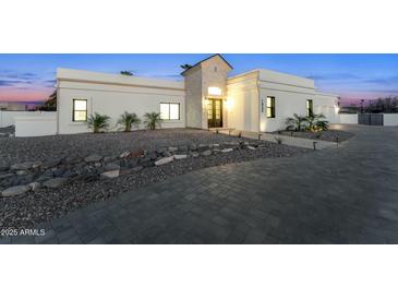 Elegant exterior view of a modern home with a well-manicured stone front yard and a paved driveway at 7860 E Davenport Dr, Scottsdale, AZ 85260
