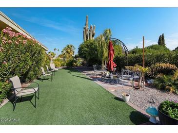 Landscaped backyard with artificial turf, seating area, and cactus at 9319 W Glen Oaks Cir, Sun City, AZ 85351