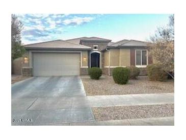 Inviting single-story home featuring a two-car garage and arched entryway, set amidst well-maintained landscaping at 15704 W Taylor St, Goodyear, AZ 85338