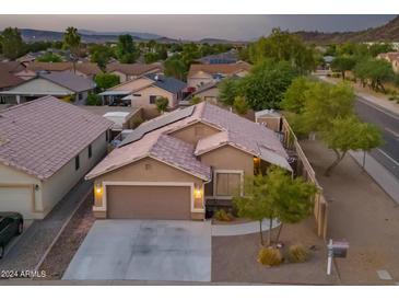 Inviting single-story home with a two-car garage, desert landscaping, and solar panels on a tile roof at 3102 W Louise Dr, Phoenix, AZ 85027