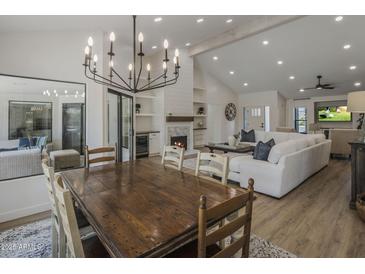 Bright, open-concept living area with a dining table, fireplace, and modern chandelier at 10685 E Cinnabar Ave, Scottsdale, AZ 85258