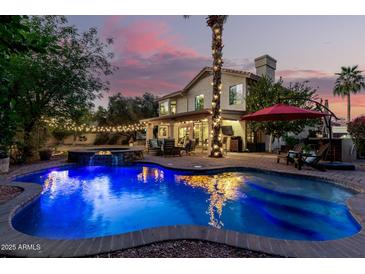 Stunning backyard featuring a pool, hot tub, covered patio, and beautiful landscaping with string lights at dusk at 211 E Dawn Dr, Tempe, AZ 85284