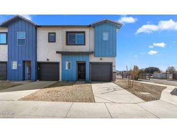 Two-story townhome with modern blue and white exterior, two-car garage, and desert landscaping at 7511 S 75Th Dr, Laveen, AZ 85339