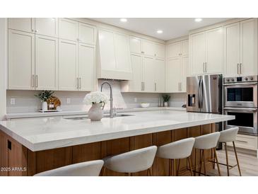 Bright kitchen showcasing a large island with marble countertop and seating, stainless steel appliances and custom cabinetry at 1723 W Brianna Rd, Phoenix, AZ 85085