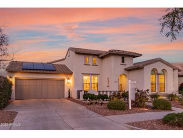 Charming two-story home with a front yard, two-car garage, and solar panels at dusk at 20914 W Cora Vis, Buckeye, AZ 85396