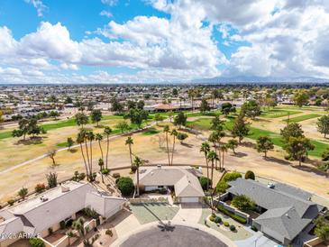 Expansive aerial view of a charming home on a golf course, with lush landscaping and beautiful desert surroundings at 9735 W Country Club Dr, Sun City, AZ 85373