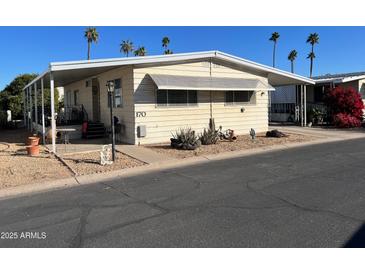 Tan single-wide mobile home with covered carport and desert landscaping at 11411 N 91St Ave # 170, Peoria, AZ 85345