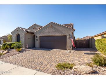 Charming single-story home with a well-manicured yard and a brick driveway, American flag, and neutral tones at 15804 N 109Th Dr, Sun City, AZ 85351