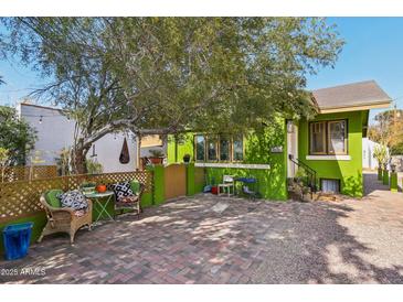 Charming green home featuring a brick driveway, a large shade tree and outdoor seating area at 1638 E Earll Dr, Phoenix, AZ 85016