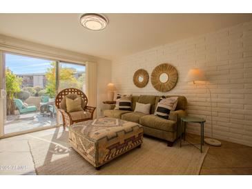 Bright living room featuring a comfortable olive sofa, patterned ottoman, and sliding door access to an outdoor patio at 4354 N 82Nd St # 137, Scottsdale, AZ 85251