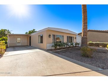 Tan single-wide manufactured home with carport and landscaped yard at 5807 E Leonora St, Mesa, AZ 85215