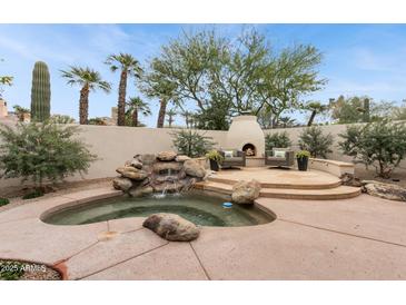 Gorgeous backyard with a rock waterfall feature, in-ground spa, and outdoor fireplace at 7705 E Doubletree Ranch Rd # 56, Scottsdale, AZ 85258