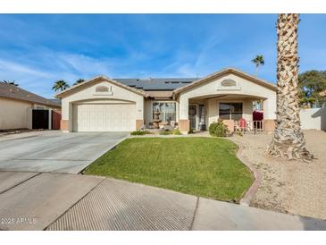 Single-story home with a landscaped lawn, two-car garage, and solar panels at 12858 W Wilshire Dr, Avondale, AZ 85392