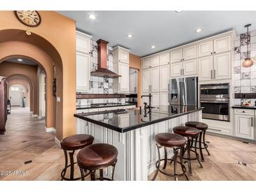 Spacious kitchen features an island with seating, stainless steel appliances, and custom cabinets at 20620 W Walton Dr, Buckeye, AZ 85396