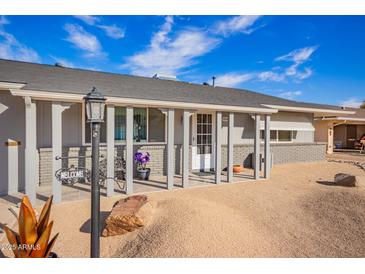 Ranch style home with covered porch, landscaping, and a two-car garage at 10144 W Cumberland Dr, Sun City, AZ 85351