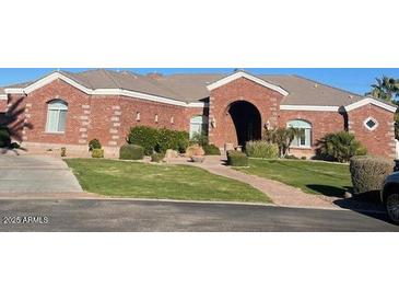 Expansive brick home featuring an arched entryway, manicured lawn, and mature landscaping at 2222 N Val Vista Dr # 2, Mesa, AZ 85213