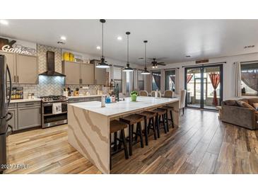 Modern kitchen boasts a large island, stainless steel appliances, and hardwood floors at 38100 W Santa Clara Ave, Maricopa, AZ 85138