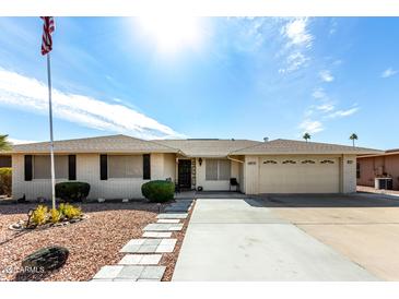 White brick ranch home with landscaped yard, two-car garage, and flagpole at 9719 W Newport Dr, Sun City, AZ 85351