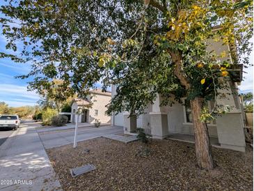 View of the exterior elevation of a two-story home with a beige stucco exterior and well maintained landscaping at 6455 W Orchid Ln, Glendale, AZ 85302