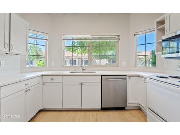 Bright kitchen features white cabinetry, stainless steel appliances, and a garden window above the sink at 955 E Vaughn Ave, Gilbert, AZ 85234