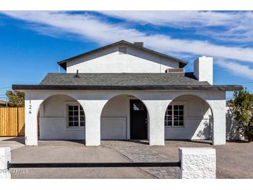 Charming white stucco home featuring arched entryway, dark door and gray tiled walkway at 124 E Beech Ave, Casa Grande, AZ 85122