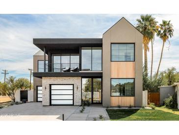 Stunning two-story modern home with a beautiful combination of stucco, brick, and wood accents and a well manicured lawn at 4445 E Roma Ave, Phoenix, AZ 85018
