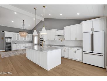 Beautiful kitchen featuring white cabinetry, marble countertops, stainless steel appliances and gorgeous hardwood flooring at 9136 N 81St St, Scottsdale, AZ 85258