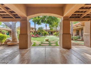 View of the backyard featuring a lush lawn, mature trees, and an inviting outdoor living space at 11505 E Cochise Dr, Scottsdale, AZ 85259