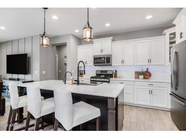 Bright kitchen features white cabinets, a large island with seating, and modern appliances at 1437 W Smoke Tree Ave, San Tan Valley, AZ 85140