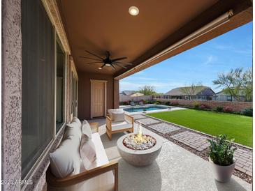 Inviting covered patio with a fire pit and a view of the pool and green lawn at 18509 W Galveston St, Goodyear, AZ 85338