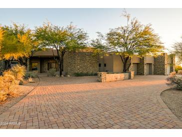 Expansive home showcasing a stone facade, mature trees, and a brick driveway leading to a multi-car garage at 37870 N 98Th Pl, Scottsdale, AZ 85262