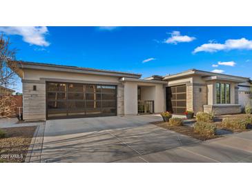 Beautiful home featuring a large driveway, glass garage doors and a well-manicured lawn at 3882 E Andalusia Ave, Gilbert, AZ 85298