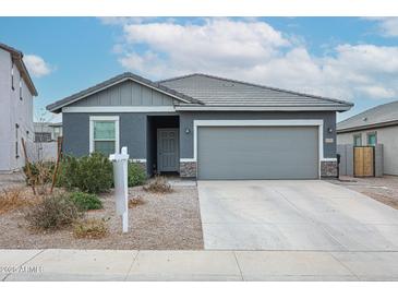 Charming single-story home with a gray exterior, well-manicured lawn, and attached two-car garage at 8314 S 64Th Dr, Laveen, AZ 85339