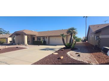 Inviting home featuring a two-car garage, desert landscaping, and mature palm trees in the front yard at 13911 W Gable Hill Dr, Sun City West, AZ 85375