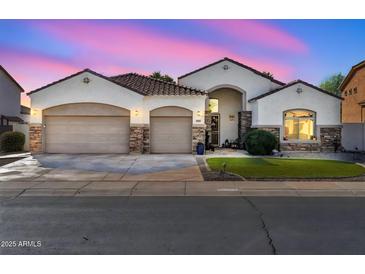 Beautiful single-story home featuring a three-car garage, stone accents, and arched entryway at 17591 W Ivy Ln, Surprise, AZ 85388