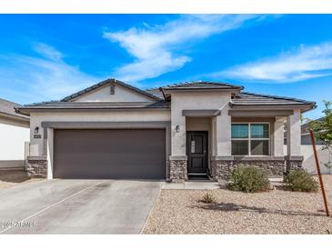 Charming single-story home featuring a stone-accented facade, gray trim, and a two-car garage at 4051 S 243Rd Dr, Buckeye, AZ 85326