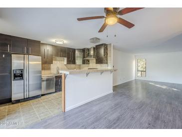 Open kitchen featuring dark cabinets, stainless steel appliances, and an eat-in breakfast bar at 4950 N Miller Rd # 135, Scottsdale, AZ 85251