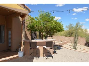 Relaxing outdoor bar area with a charming stone bar, seating, and beautiful desert landscaping for entertaining at 509 E Seco Pl, Phoenix, AZ 85086