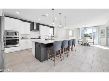 Modern kitchen boasts white cabinets, stainless steel appliances, and a large center island with seating at 1957 W Lonesome Trl, Phoenix, AZ 85085