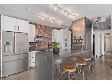 Modern kitchen featuring stainless steel appliances, a brick backsplash, and seating at the island at 207 W Clarendon Ave # B22, Phoenix, AZ 85013